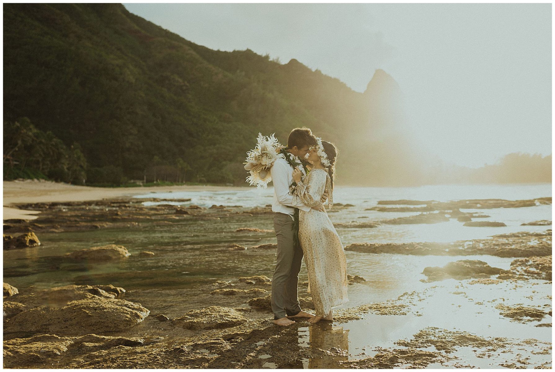 bride dressed in a gold dress kissing her groom, dressed in Hawaiian attire during their elopement on the beach of Kauai