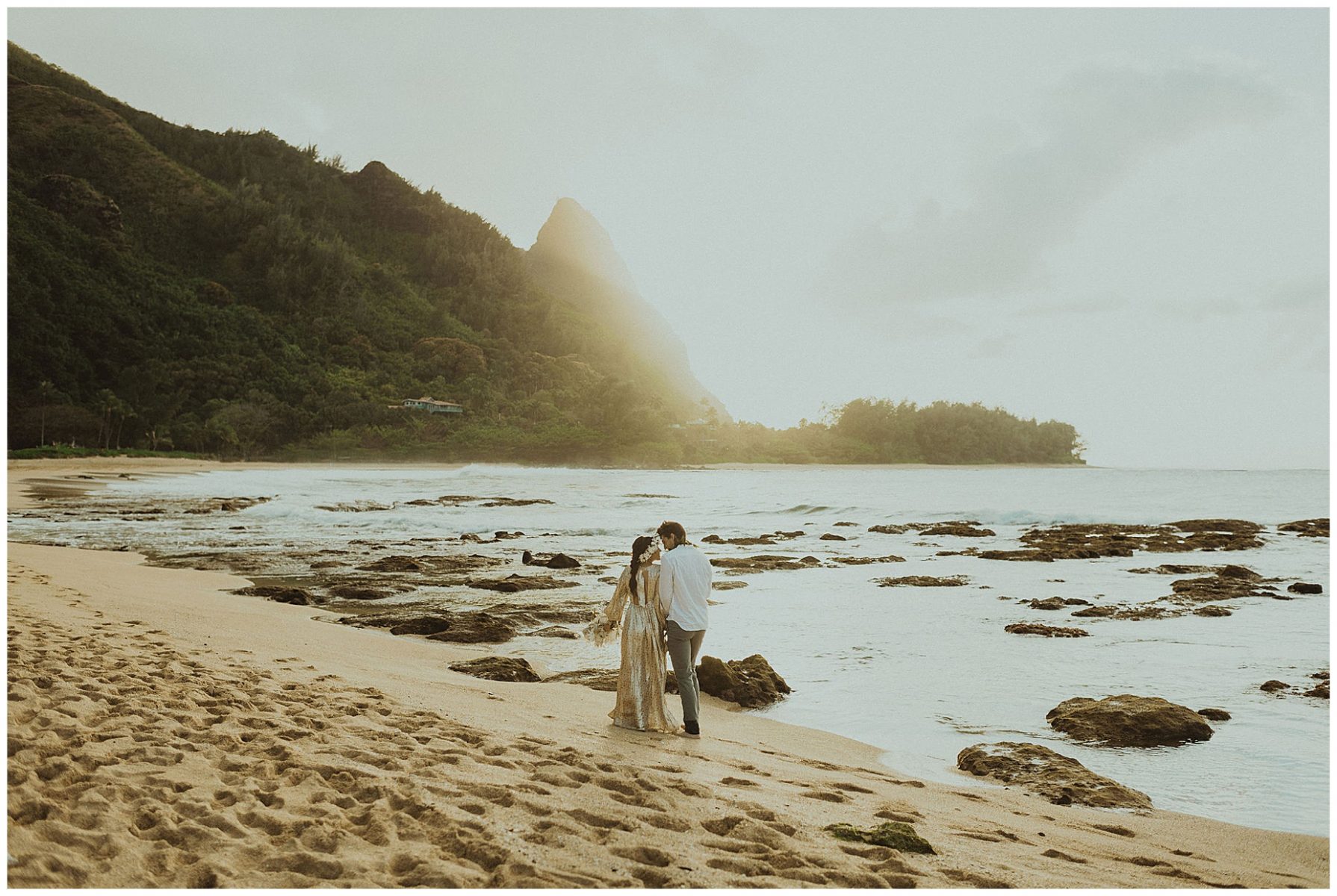 bride dressed in a gold dress holding hands with her groom, dressed in Hawaiian attire during their elopement on the beach of Kauai