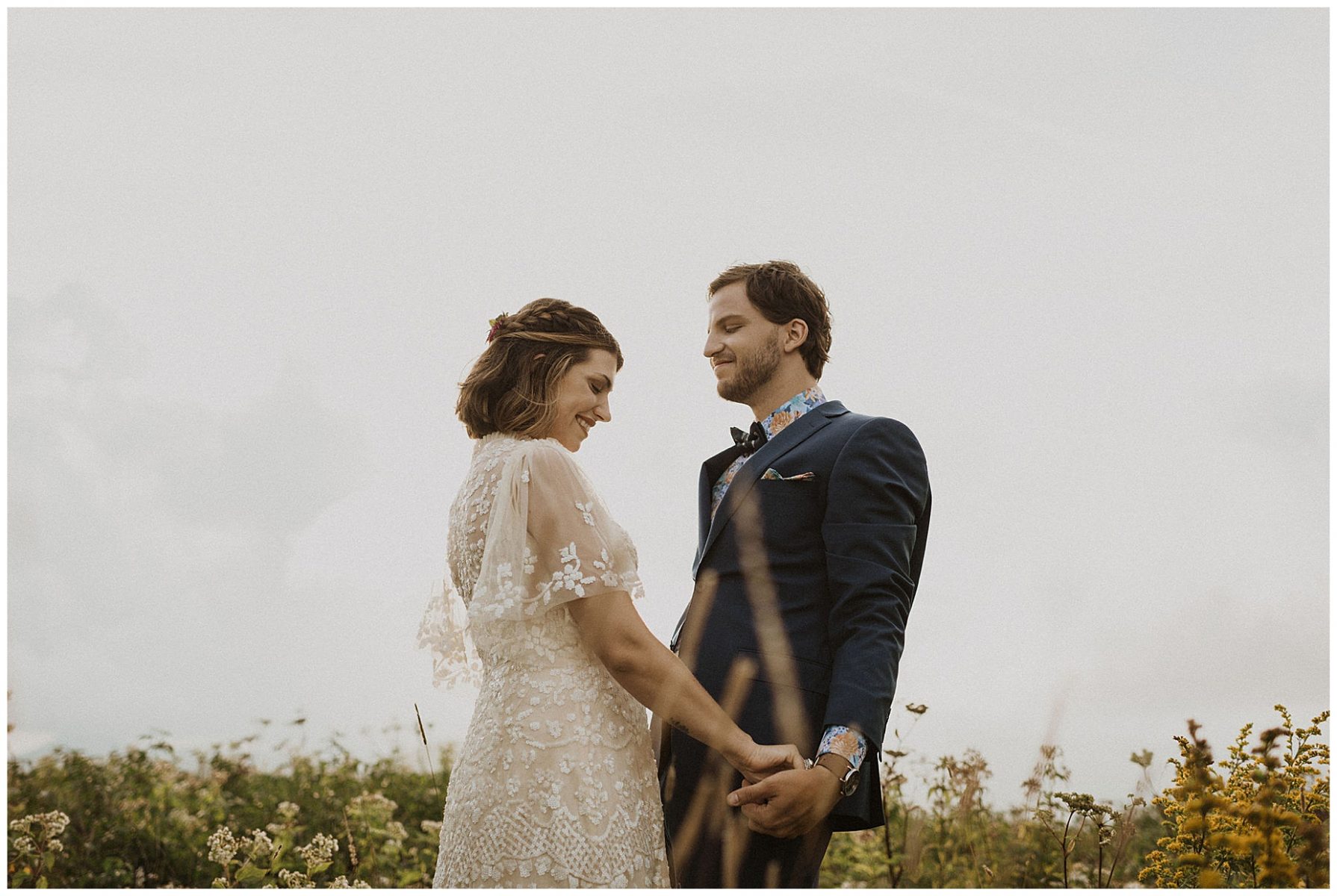 bride and groom holding hands, walking through the wildflowers on their elopement day